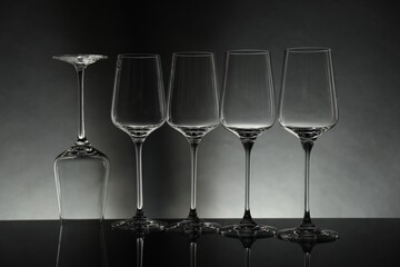 Many empty clean glasses on mirror surface against grey background