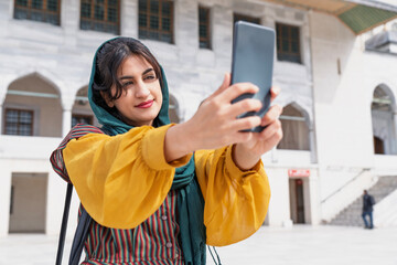 Young Muslim woman taking selfie while traveling