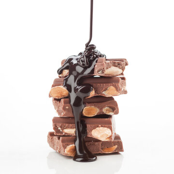 Melted chocolate drips over stacked almond filled chocolate bars