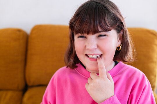 Young girl showing off her missing milk tooth at home