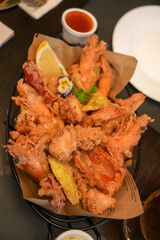 A delicious platter of golden-fried seafood, garnished with fresh herbs and served with a creamy dipping sauce