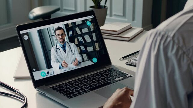 Over-the-shoulder angle of a person in a video call with a doctor on a laptop, highlighting telemedicine in a modern office setting.
