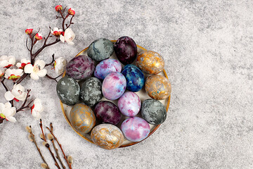 Easter celebration concept, Easter marble eggs dyed with natural hibiscus tea with sakura branch on concrete gray background. holiday card and ideas for preparing for the great holiday