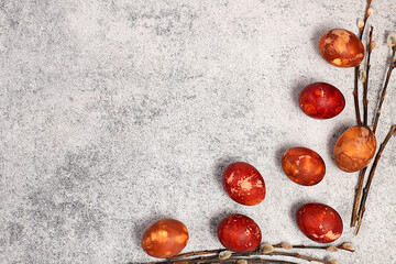 Easter celebration concept, Easter marble eggs dyed with natural onion peel and curcumin, with willow branch on concrete gray background. holiday card and ideas for preparing for the great holiday