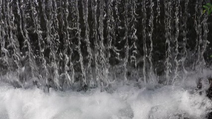 Streams of crystal clear water fall into the river creating splashes and bubbles, slow motion - Powered by Adobe