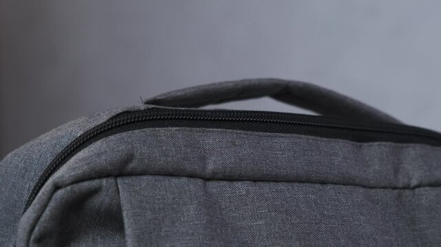 Men's hands zip up the backpack on both sides and pick up the bag close up
