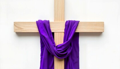 Wooden cross draped with purple fabric on white background