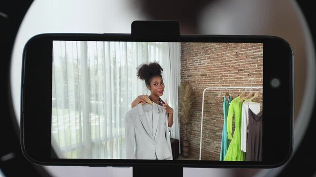 Rear view behide smartphone screen recording woman influencer shoot live stream vlog video review clothe crucial social media or blog. Girl with apparel studio lighting for marketing broadcast online