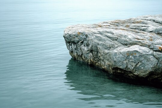 Serene coastal rock formation partially submerged in tranquil, teal water.