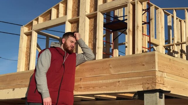 Sad angry man having problems with construction of her wooden house