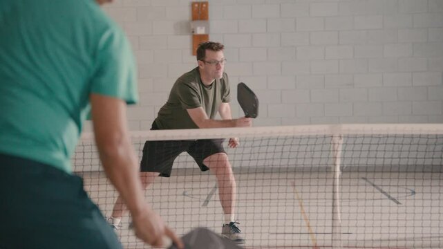 Adult pickleball players having a rally in a community gym