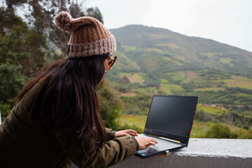 Mujer joven atractiva trabajando en laptop al aire libre durante sus vacaciones en la naturaleza.estilo de vida turista.