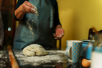 Chef sprinkling flour over dough while preparing homemade bread, pizza, or other baked goods in a cozy kitchen, creating a warm and inviting culinary atmosphere