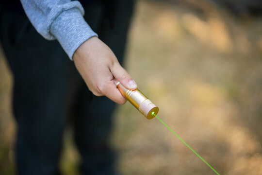 A laser pointer with a green glow. The image of a man with a green laser pointer.Laser blinding.Dangerous teen games.