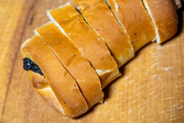 Freshly baked poppy seed bun loaf sliced on a wooden cutting board