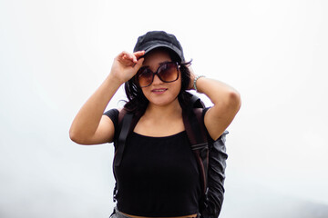 Turista caminante joven atractiva con top negro y mochila de pie en fondo blanco	
