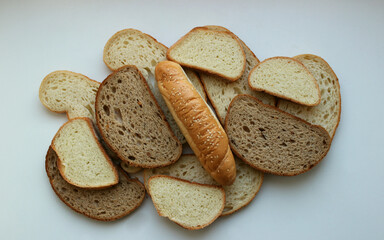 Different types of bread cut into slices and a long bun on them isolated on white table flat lay image