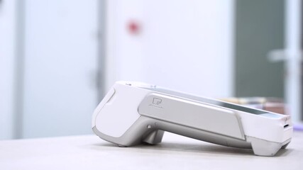 Pay by phone on electronic payment machine or card reader. E-money at cashless wallet. Female hand with pos-terminal and cellphone closeup. Client pays for the procedure in modern beauty clinic.