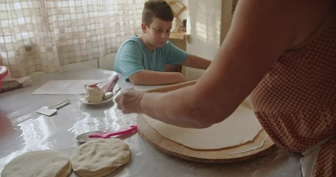 A grandmother and grandson share a special moment making traditional flat bread. Love, family, and baking.