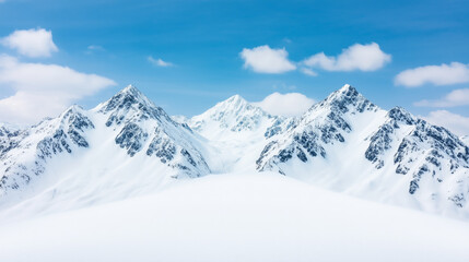 Naklejka premium A breathtaking view of snow-capped mountains with sharp peaks, surrounded by a bright blue sky and gentle clouds, winter