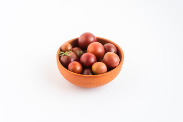 A terracotta bowl filled with fresh cherry tomatoes on a white background.