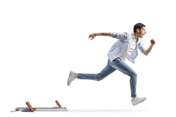 Full length profile shot of a young man in jeans running from start blocks