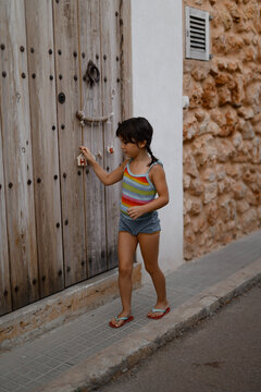 Young girl playing with a door knocker in rustic setting