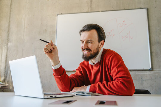 Man smiling while working on laptop in a casual office