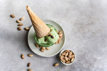 Homemade Pistachio Ice Cream in Cone with Nuts on Grey Background