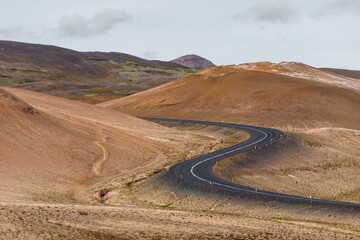 Curved Roadway Through Vibrant Desert Landscape with Rolling Hills and Scenic Views of Nature's Unique Colors and Texture