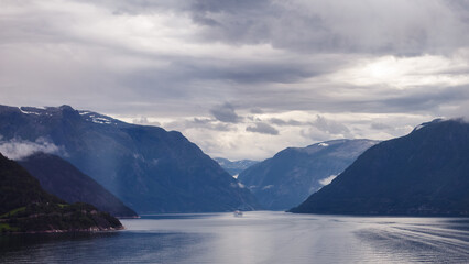 Breathtaking Norwegian Fjord with Majestic Mountains and Overcast Sky Reflected in Calm Water - A Scenic View of Nature's Beauty and Wonder Awaiting Exploration and Adventure