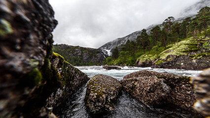 A Beautiful Mountain Stream Landscape Surrounded by Lush Greenery and Rocky Terrain Under a...