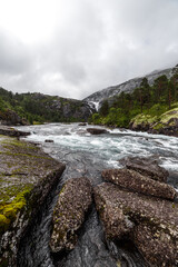 A Serene River Surrounded by Lush Greenery and Majestic Mountains Under Cloudy Skies in a Picturesque Landscape, Perfect for Nature Lovers and Adventure Seekers Alike