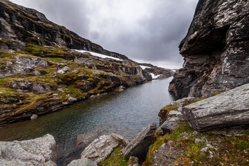 Stunning Mountain Landscape with Tranquil Waters Reflecting a Dramatic Sky in a Remote Wilderness Region Surrounded by Boulders and Lush Greenery