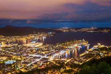 Obraz premium Stunning Aerial View Over the Vibrant Cityscape of Bergen, Norway, Showcasing its Scenic Harbor and Brightly Lit Buildings Against a Twilight Sky