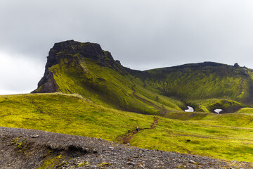 A Majestic View of Green Hills and Rugged Peaks Under a Brooding Sky, Capturing the Natural Beauty and Wilderness of an Untamed Landscape in Icelandic Highlands