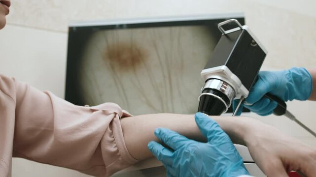 A dermatologist examines and analyzes the skin of a young patient in a modern clinic using advanced equipment. Concept skin research, diagnosis of oncological skin diseases.