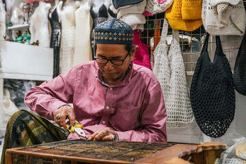 Balinese craftsman focusing on traditional crochet bag creation