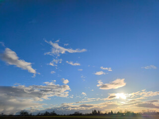 The sun is low over the fields and meadows - the first sunset glow appears in the clouds
