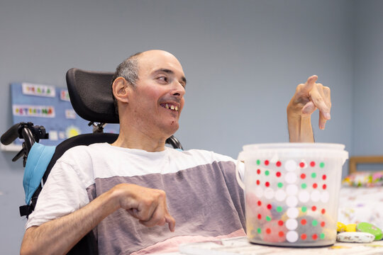 Man with a Mental Disability in Wheelchair Enjoying a Therapy Activity