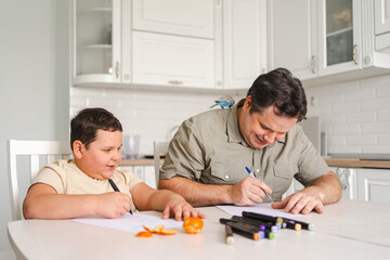 Father and son drawing together at home with pet bird