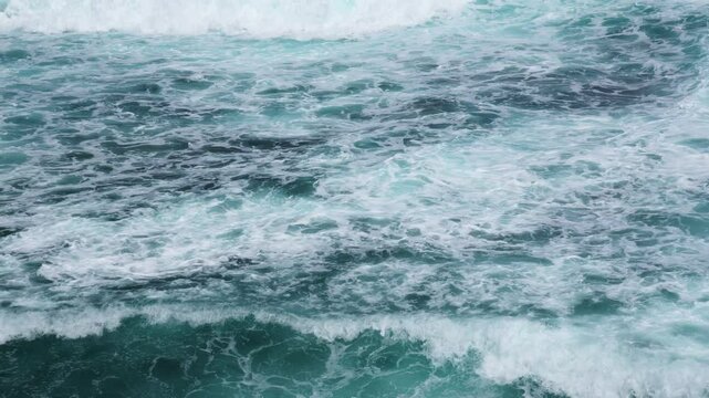 Aerial footage of dynamic ocean surface with rolling waves and sea foa. Powerful seascape with churning waves and aqua blue water.Ocean in motion. Oceanic symphony
