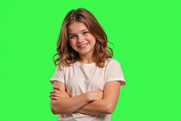 Fototapeta premium Cheerful 10-Year-Old Girl with Brown Hair and Smile Posing with Crossed Arms on Green Screen Background