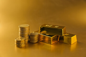 Gold bars and coins on shiny background