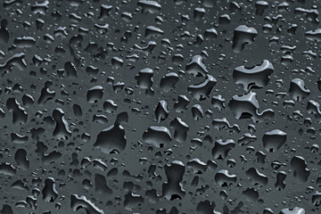 Water drops on black glass surface, closeup