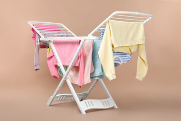 Drying rack with fresh clean laundry on beige background