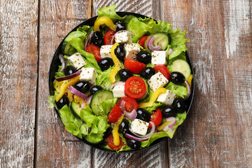 Delicious fresh Greek salad on wooden table, top view