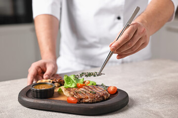 Professional chef serving dish at table indoors, closeup