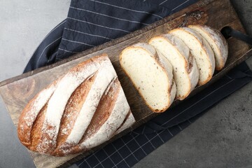 Cutting board with fresh bread on grey table, top view