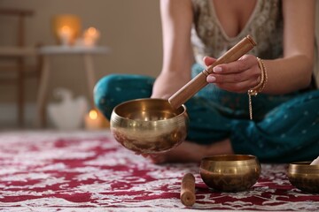 Woman with singing bowls and burning candles indoors, closeup